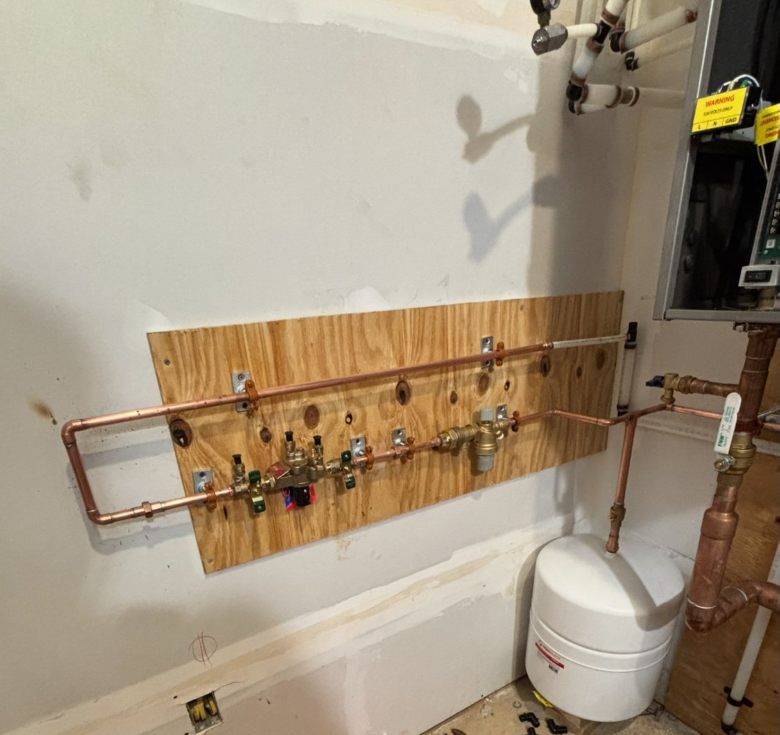 Copper supply manifold with valves mounted on a plywood backer, tied into an expansion tank