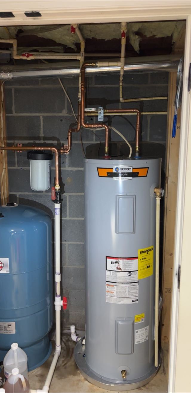 Water heater in a utility closet with copper lines, a whole-home filter and a pressure tank